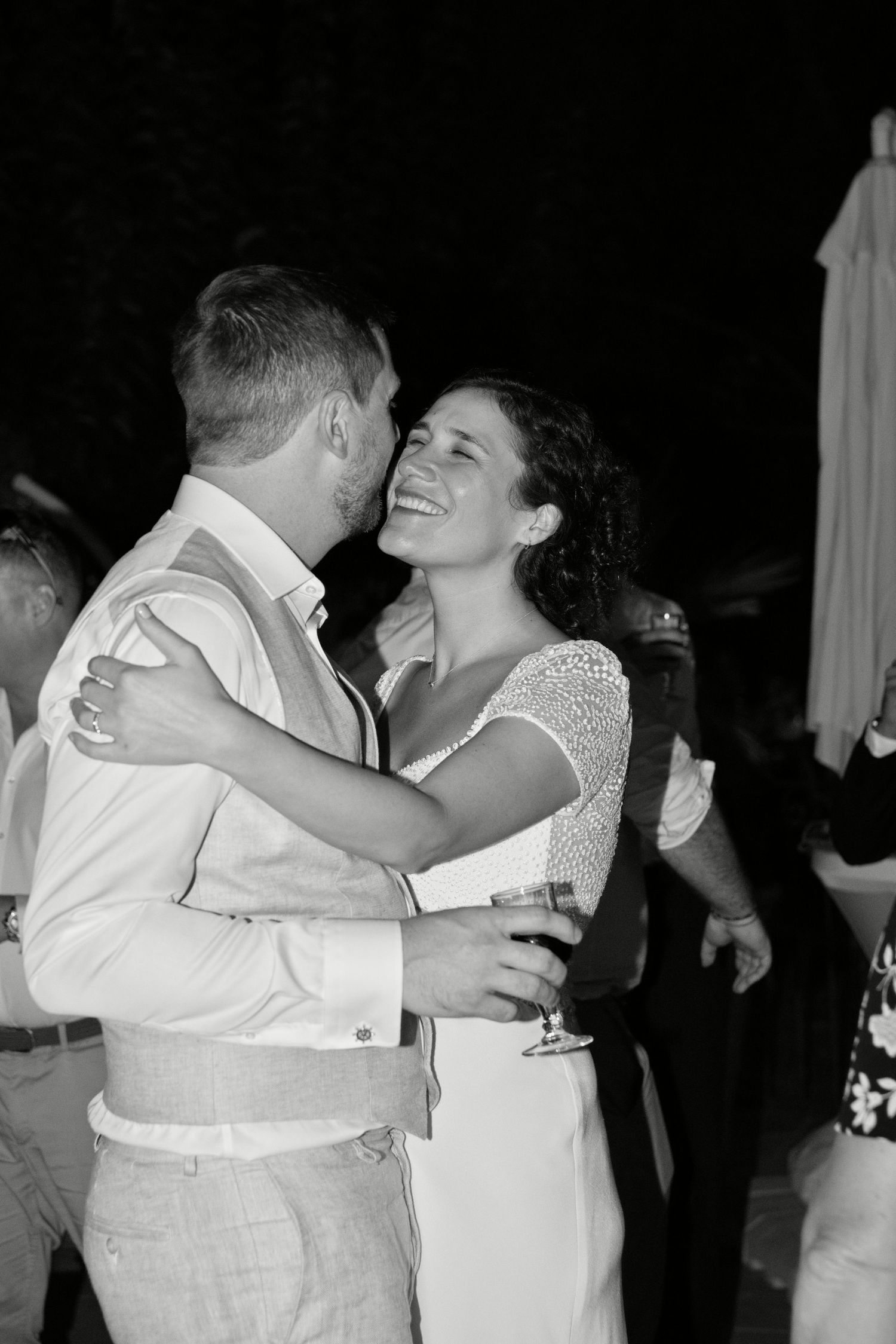 Augustine sourit dans les bras d’Ugo pendant leur soirée de mariage, en noir et blanc.