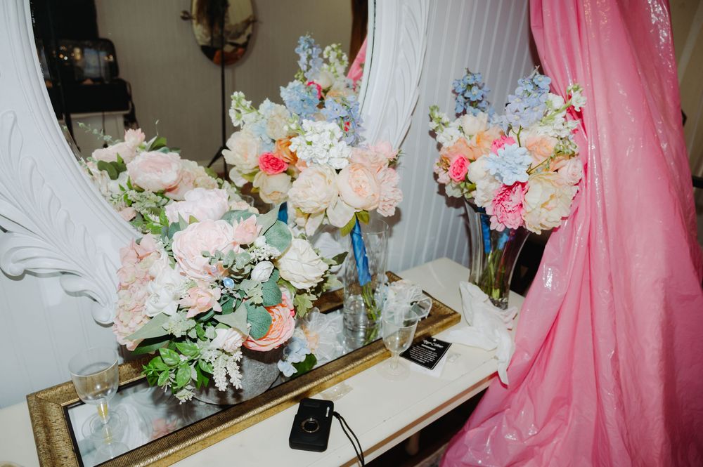 Elegant wedding bouquets with pink and blue flowers displayed on a mirrored vanity table.