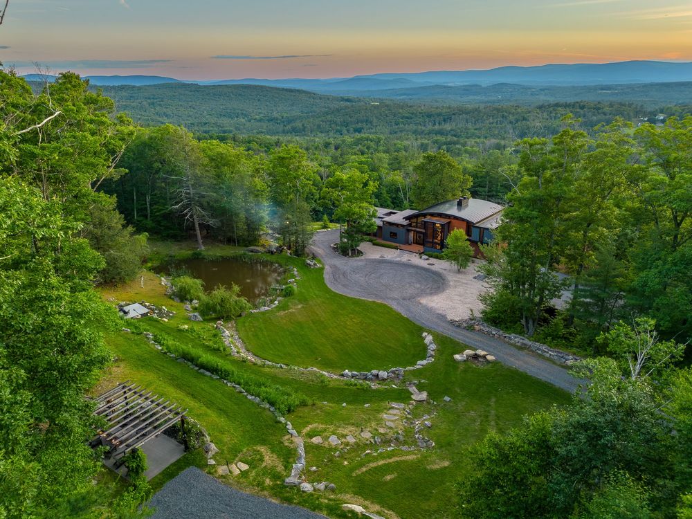 Aerial sunset view of a mountain property with sweeping valley views and landscaped grounds.
