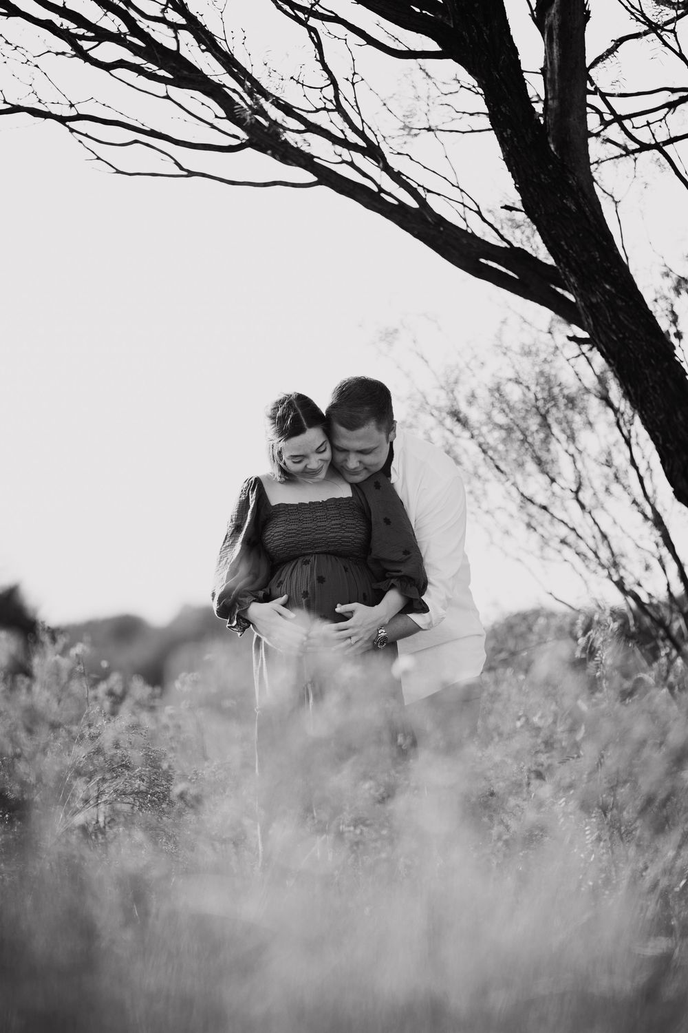 A romantic couple embraces in a dreamy black and white outdoor photoshoot with misty natural scenery.
