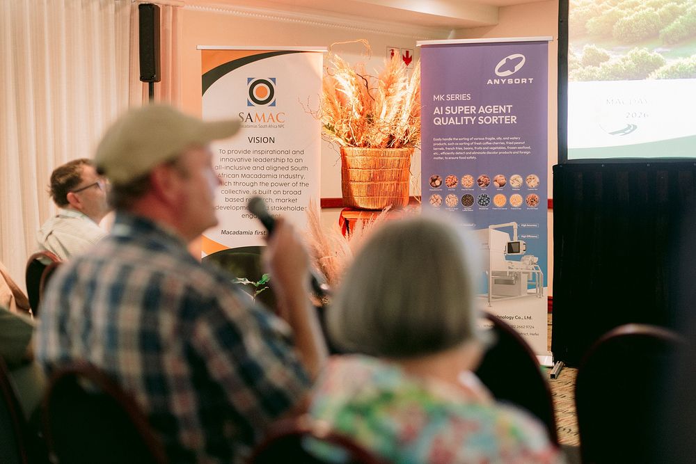 Audience members attend a conference presentation featuring AI super agent quality sorter technology display banners.