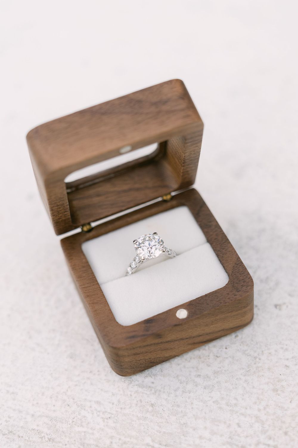 Diamond engagement ring displayed in an open wooden ring box during a proposal photography session.