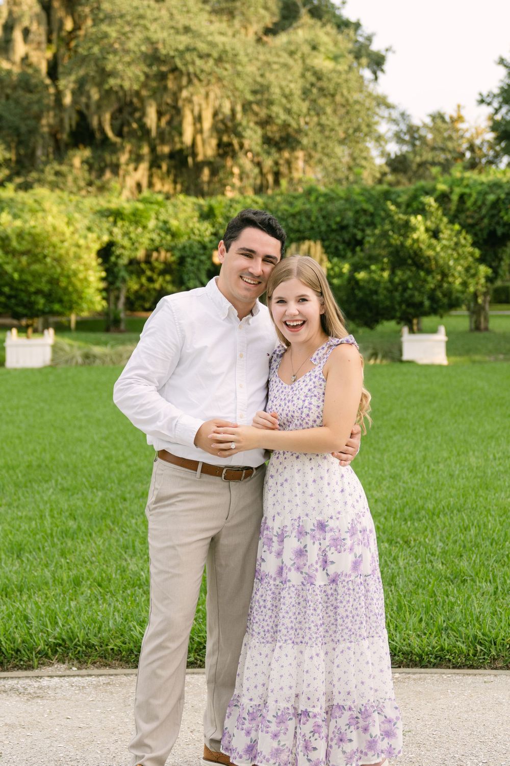 Smiling engaged couple embracing on a garden path during their Jekyll Island engagement photography session.