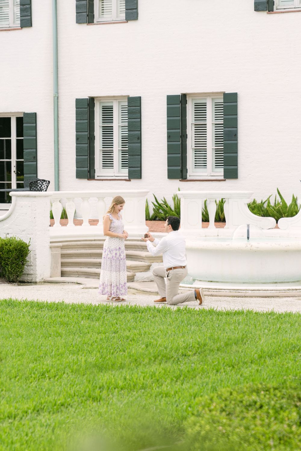 Man kneeling to proposing beside a fountain at Crane Cottage on Jekyll Island, Georgia with proposal and couples photographer Lindy Rebro