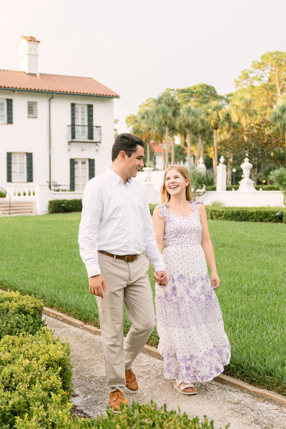 Engaged couple walking hand in hand along a garden path outside Crane Cottage on Jekyll Island, Georgia.