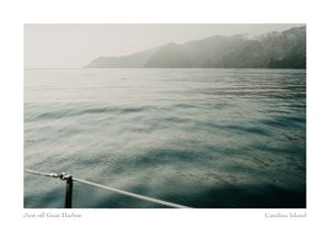 Calm gray-green ocean water off Catalina Island near Goat Harbor, with misty hills in the distance and a boat railing in the foreground.