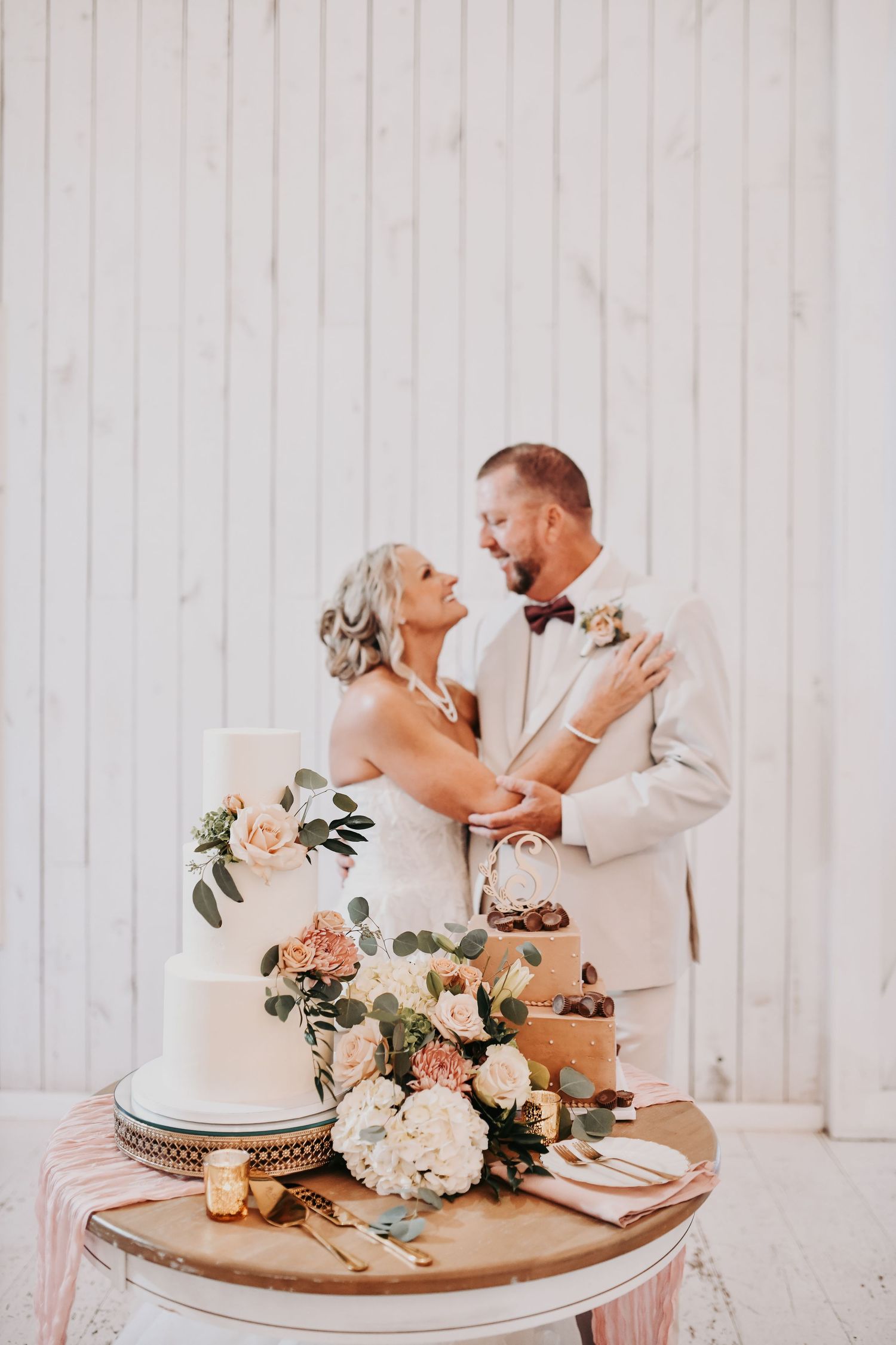 Three-tier white wedding cake styled with romantic blush wedding florals