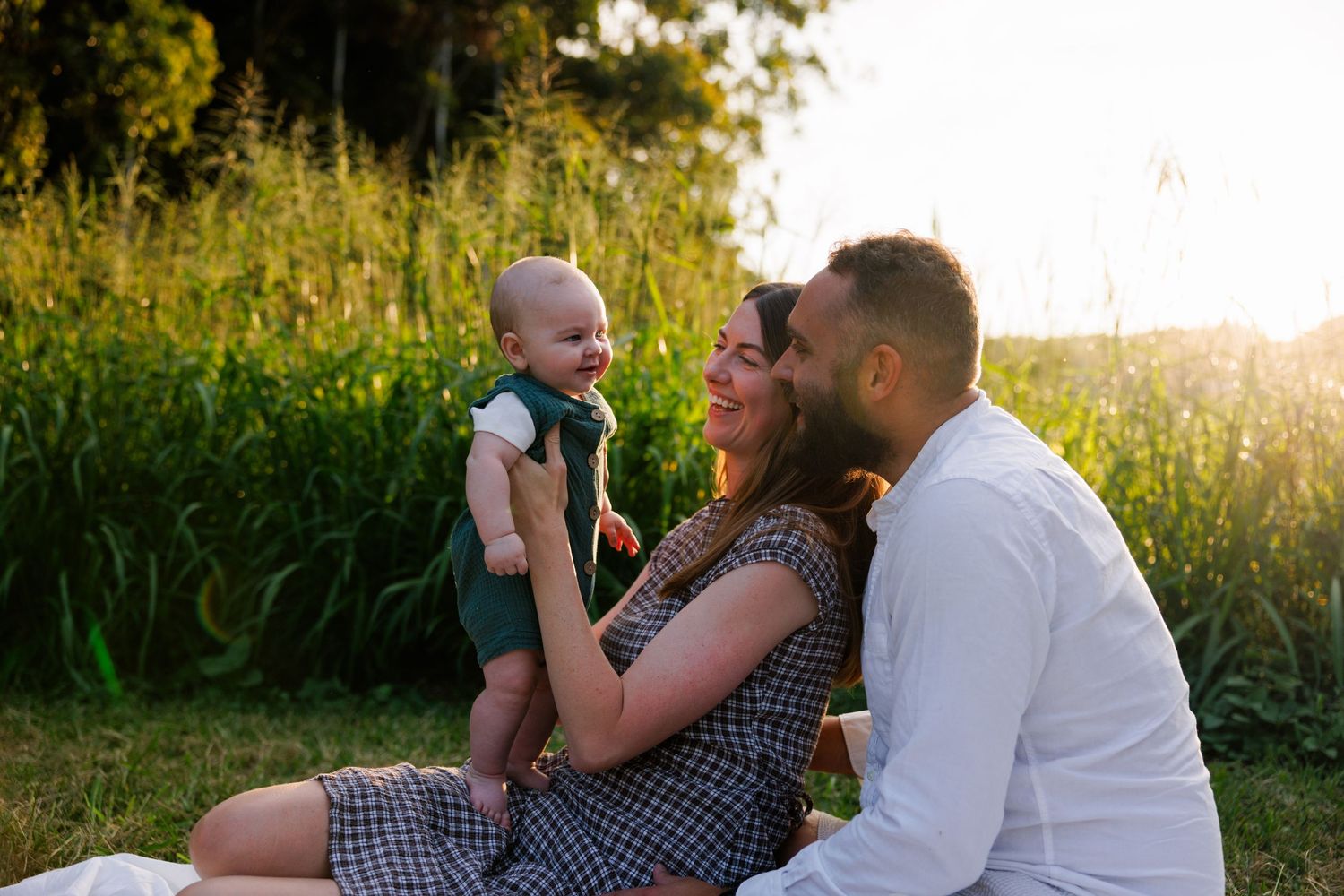 mother and father playing with baby outside