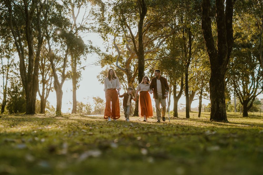 Family walking together through a sunlit autumn park surrounded by golden trees on a warm fall day.