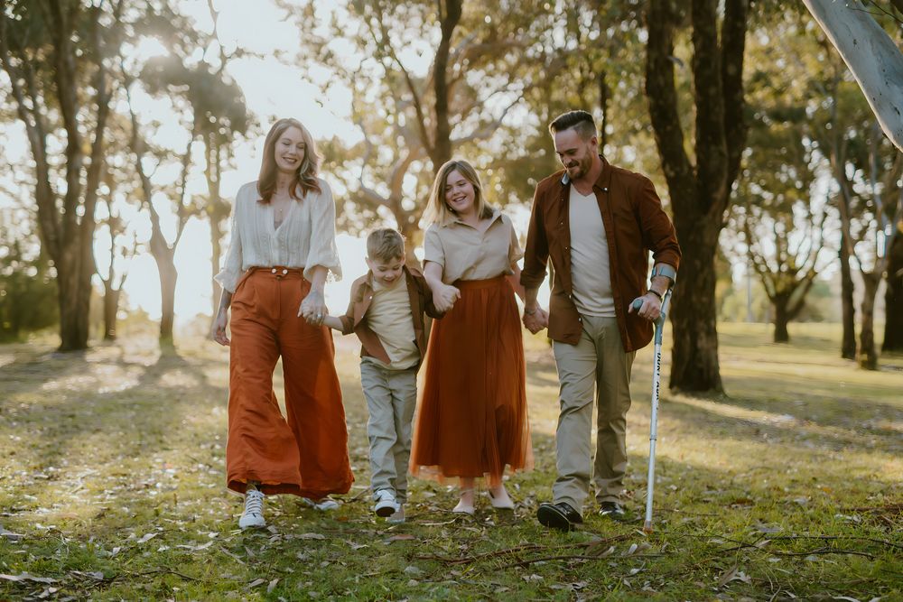 Family of four walking together through sunlit trees at Nyerimilang Park, East Gippsland