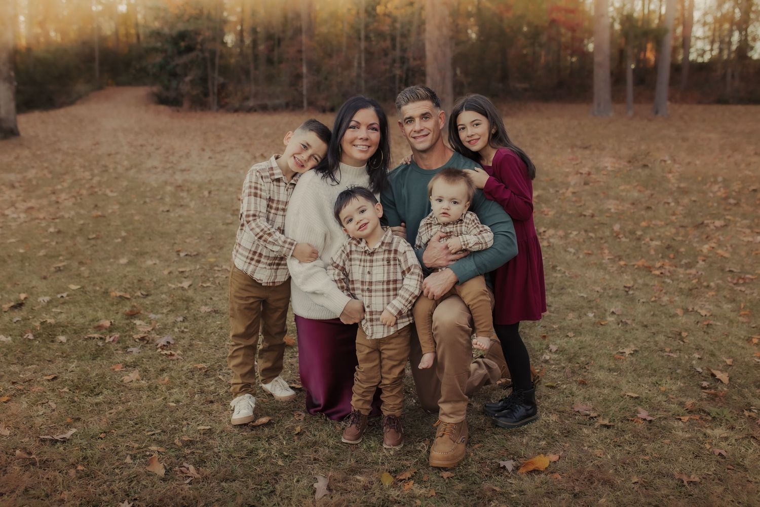 Family smiling and laughing in a field during a family session in Wimbledon