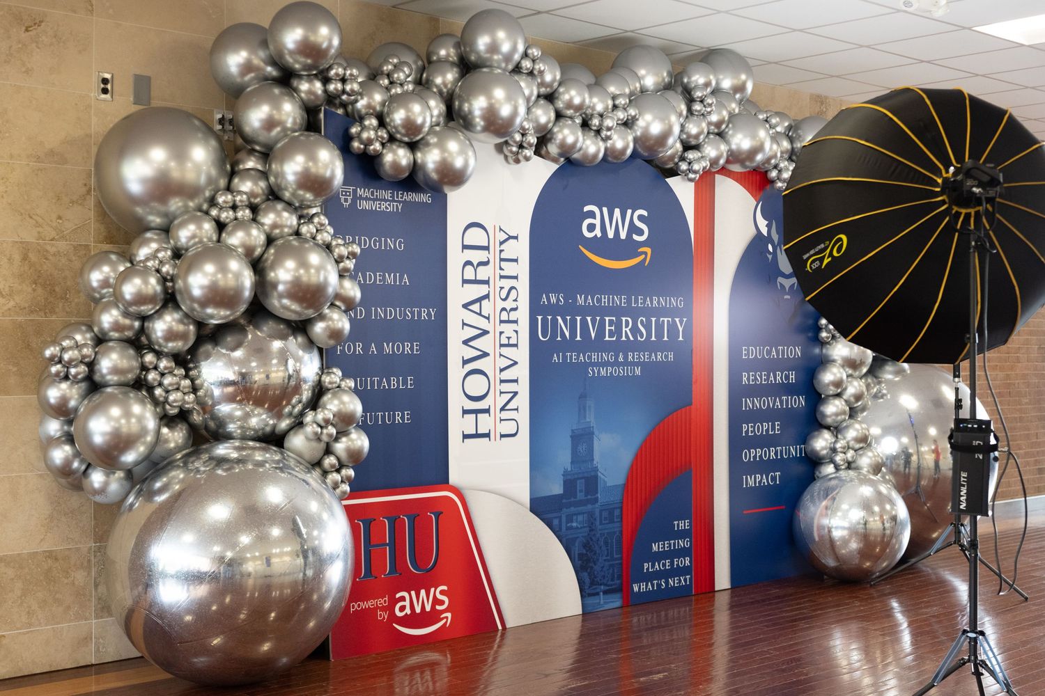 Howard University AWS partnership event display with silver balloon arch, branded banners, and photography lighting equipment.