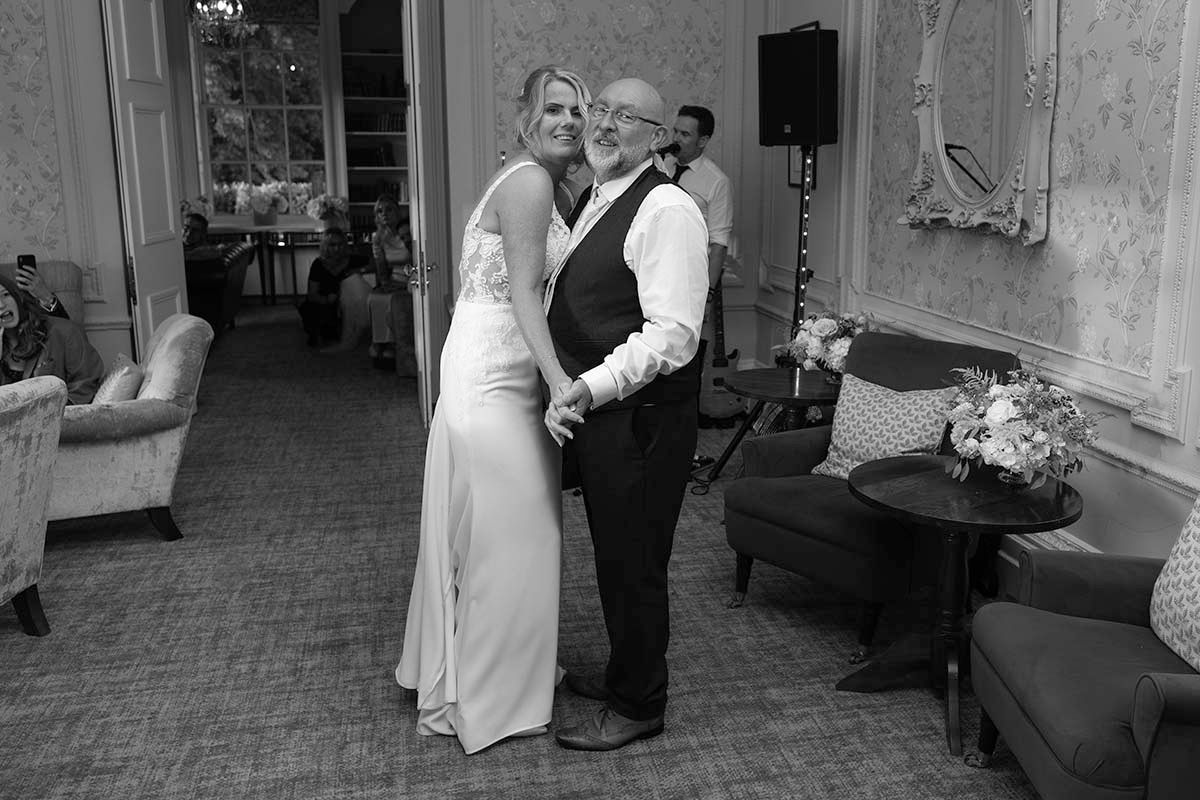Black and white photograph of the bride and groom dancing together inside the Belsfield Hotel.
