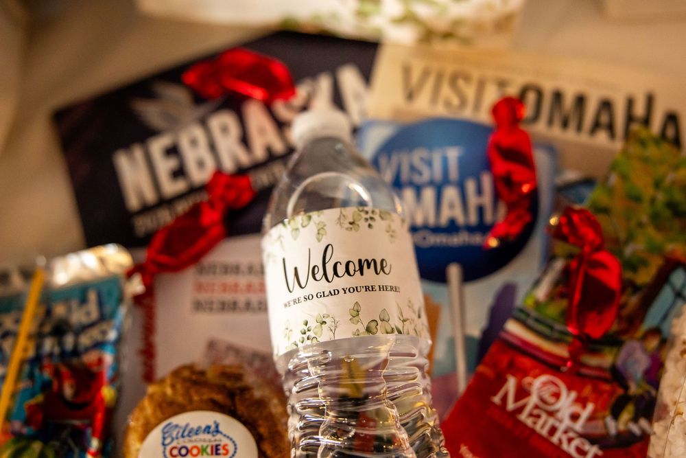 Welcome water bottle surrounded by Nebraska and Visit Omaha tourism merchandise, cookies, and red ribbon gift basket items.