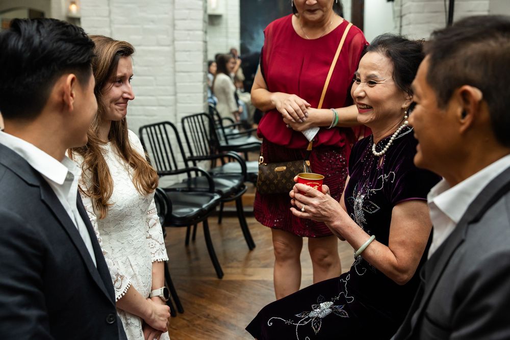 Guests socializing at an elegant indoor event, with women in formal attire sharing drinks and conversation.