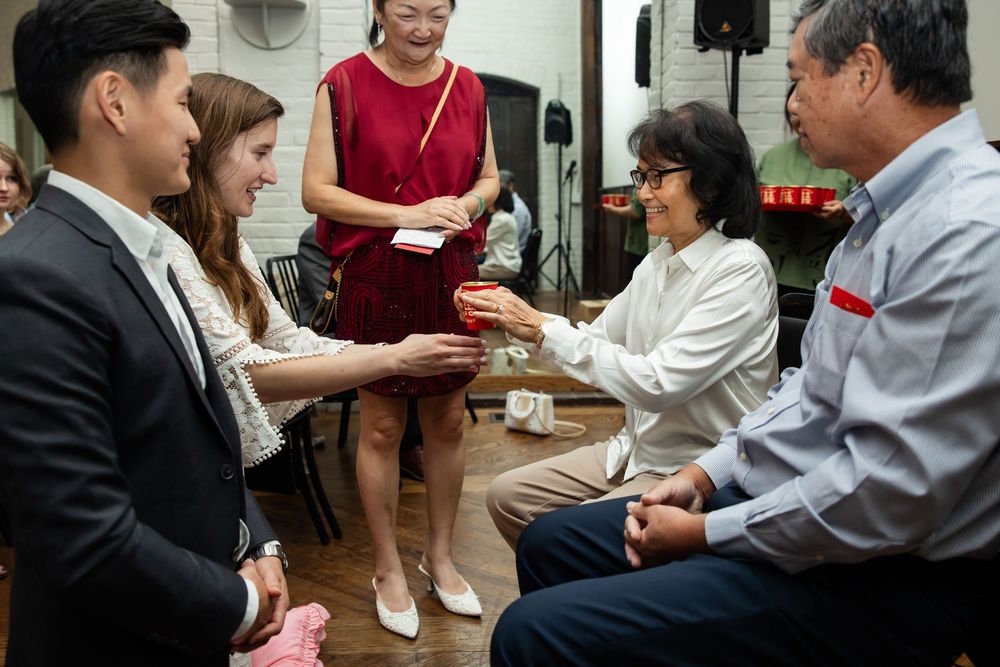 Group of people gathered indoors, exchanging gifts during a formal celebration or cultural ceremony.