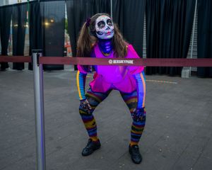 Person in colorful skull face paint and vibrant purple jumpsuit posing at Hersheypark Halloween event.