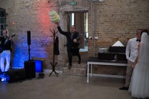 Egy személy ttortát ejt a levegőbe egy rusztikus, téglaépítésű helyszínen, kék hangulatvilágítással és rendezvénydekorációval.