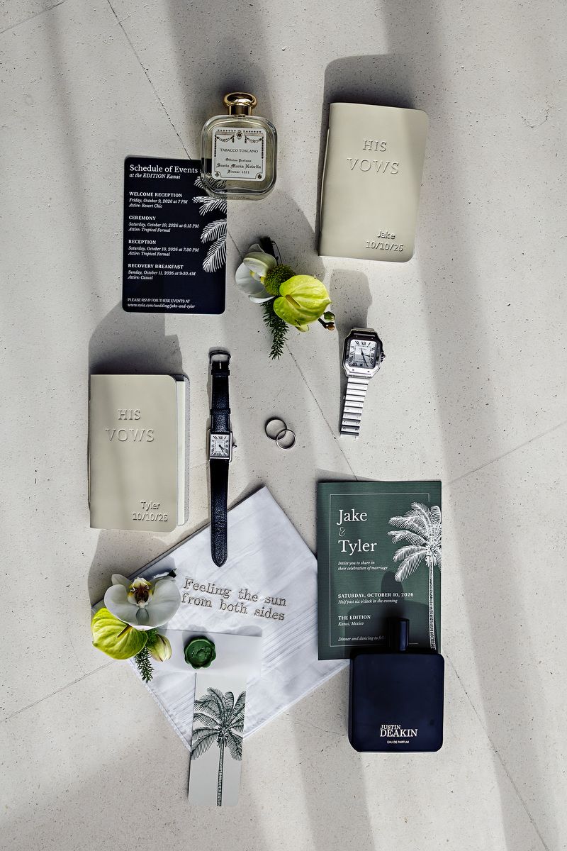 Wedding flat lay with vow books, watches, rings, cologne, and floral accents for Jake and Tyler's ceremony.