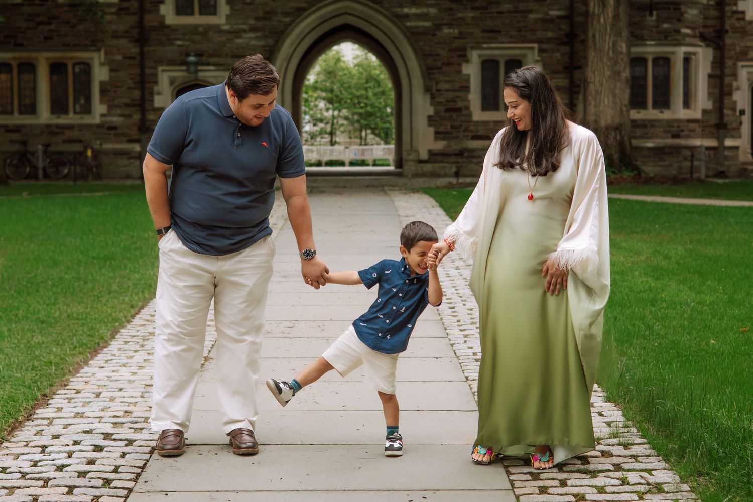 Expectant parents walking with their son on a campus path, mom in a sage gown, NJ maternity photos