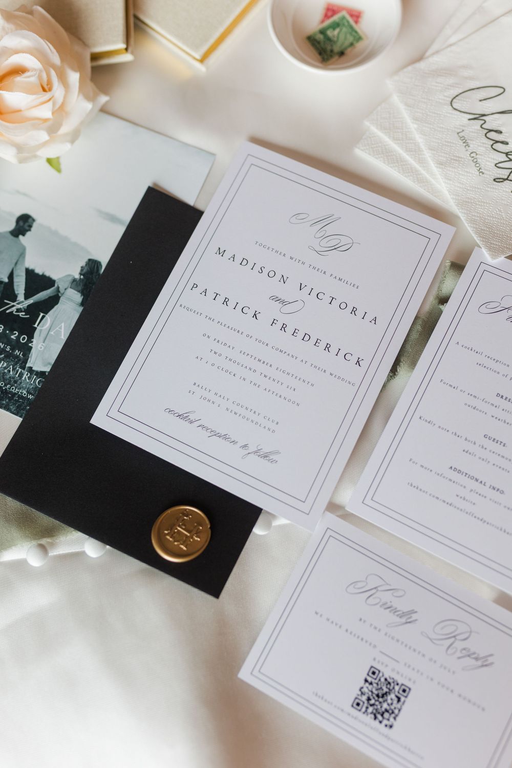 Elegant wedding invitation suite with black border, wax seal, QR code RSVP card, and floral accents on white background.