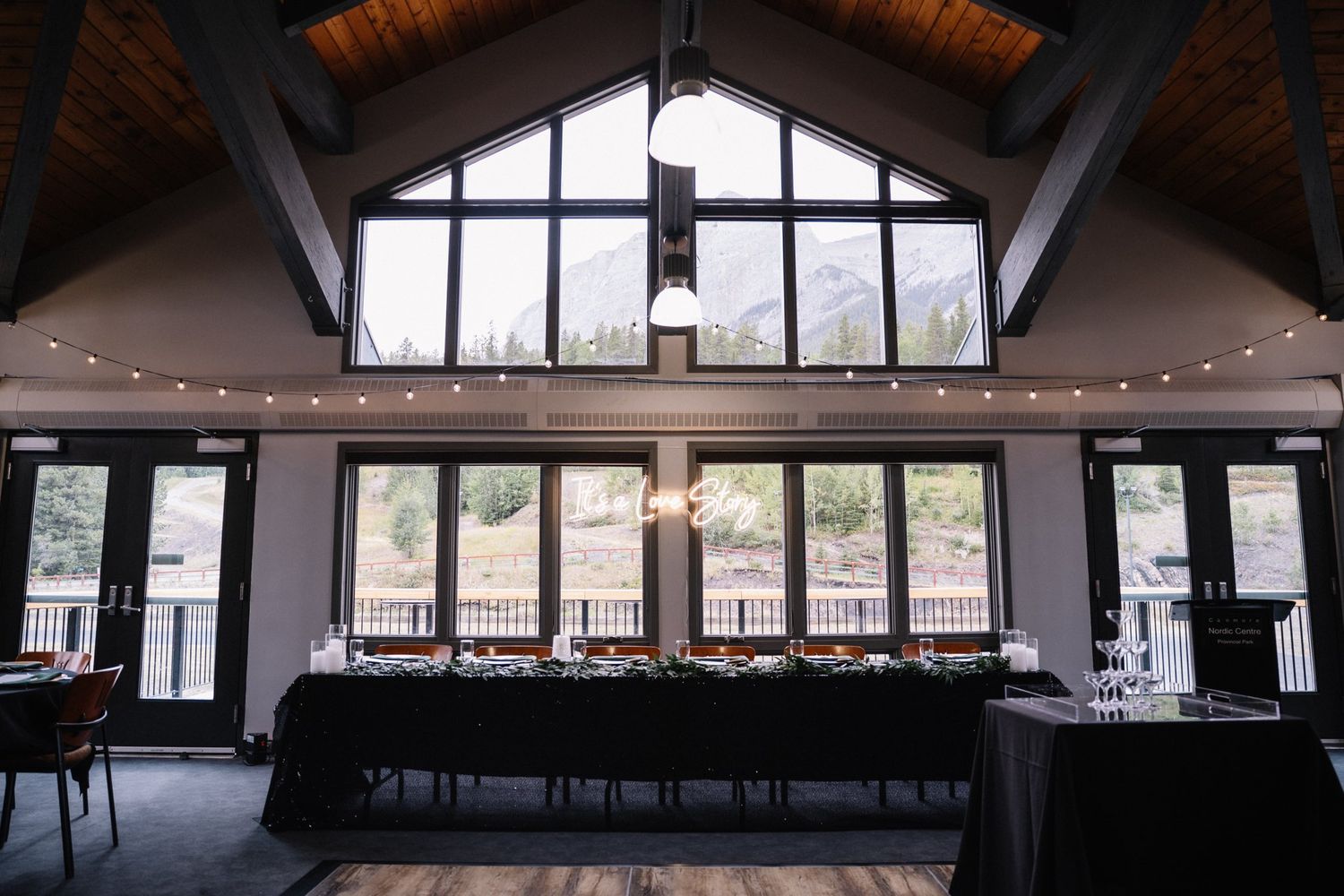 Rundleview Room wedding reception setup with string lights and mountain-view windows at the Canmore Nordic Centre