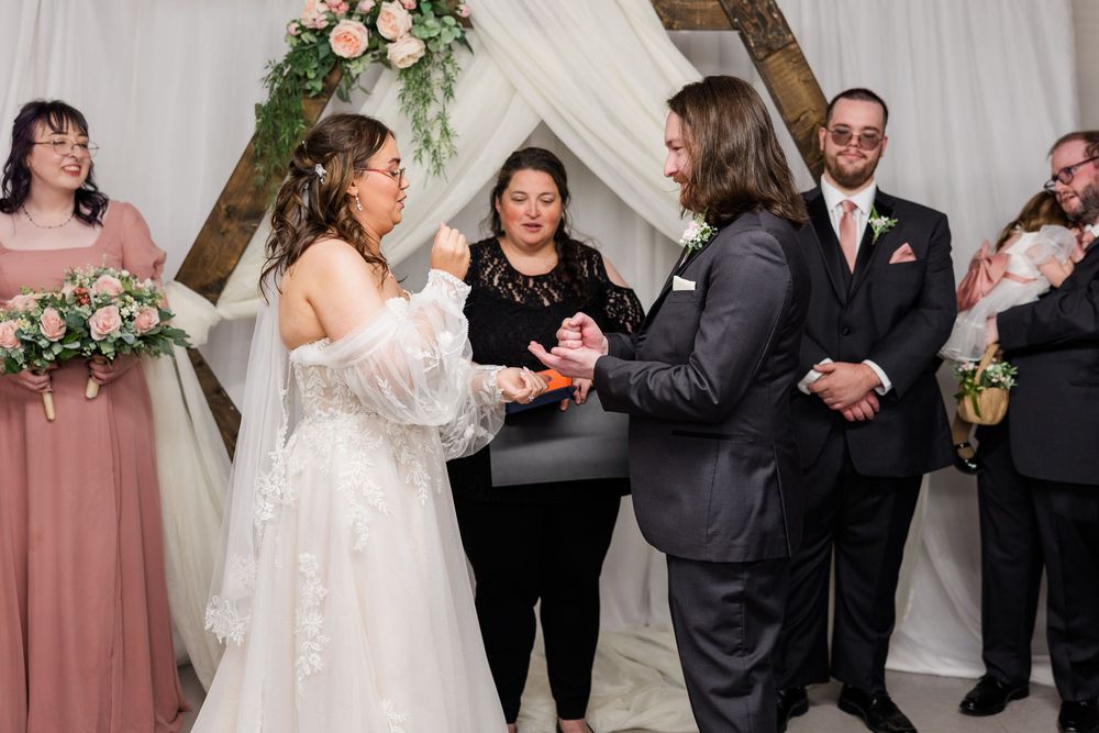 Bride and groom exchange rings at the altar during an emotional indoor wedding ceremony.