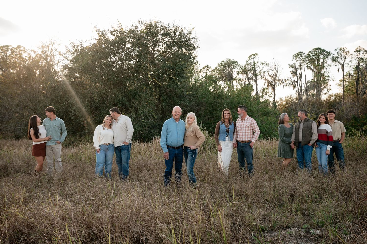 Family photo sequence in natural setting with tall grass and trees in background.