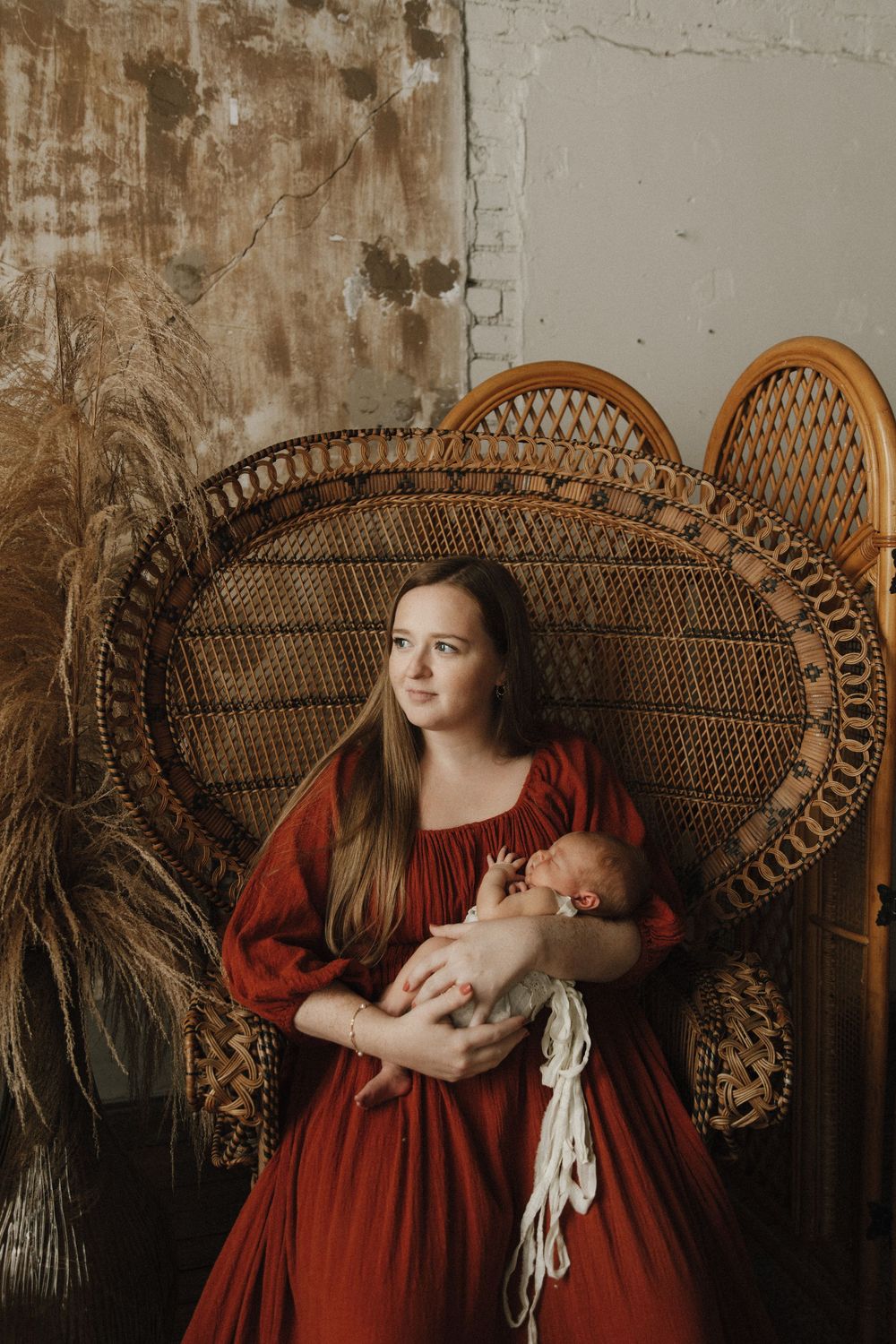 Artistic portrait in vintage style featuring a figure in a flowing red dress seated in an ornate wicker peacock chair.