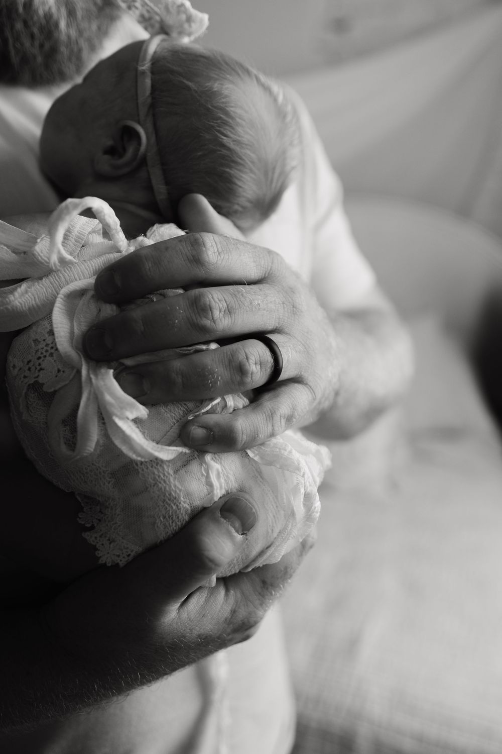 Two hands captured in close-up black and white as they gently embrace in an intimate moment.