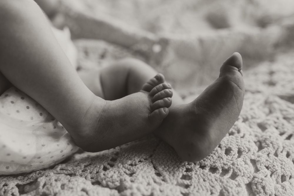 Close-up details of tiny baby feet and toes on textured blanket.
