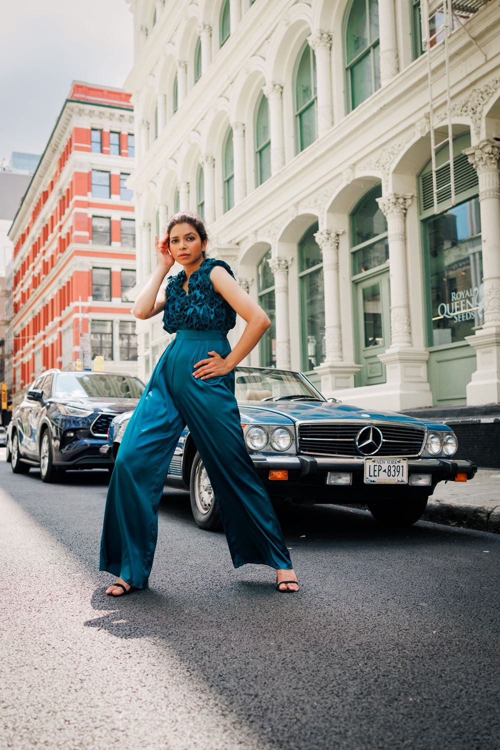 Street fashion photography with blue jumpsuit against classic architecture and vintage Mercedes car.