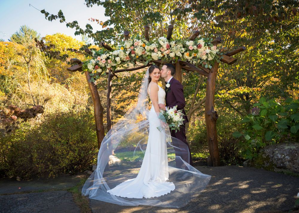 Autumn wedding portrait with flowing veil and golden foliage in background.