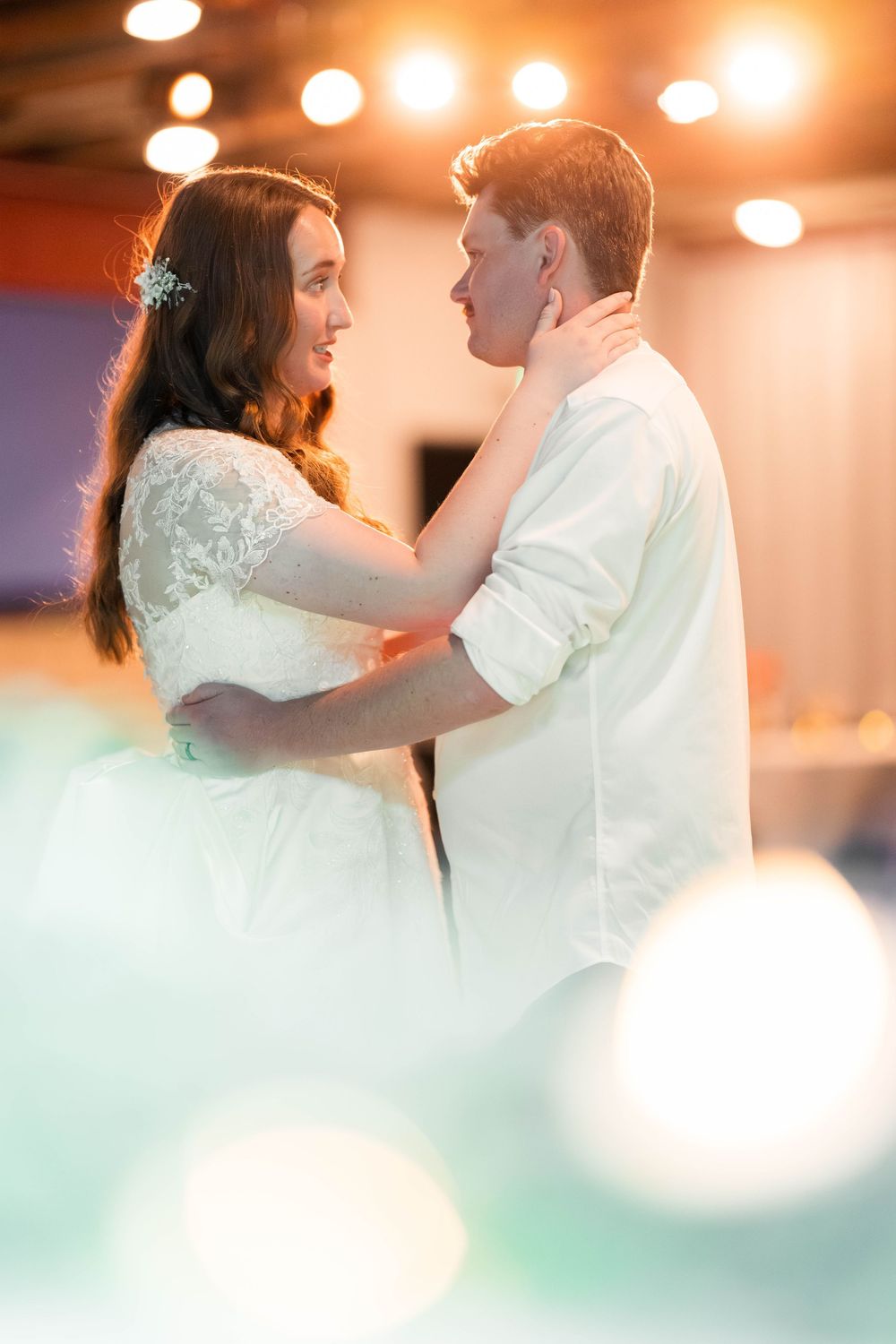a bride and groom dance at their wedding while backlit