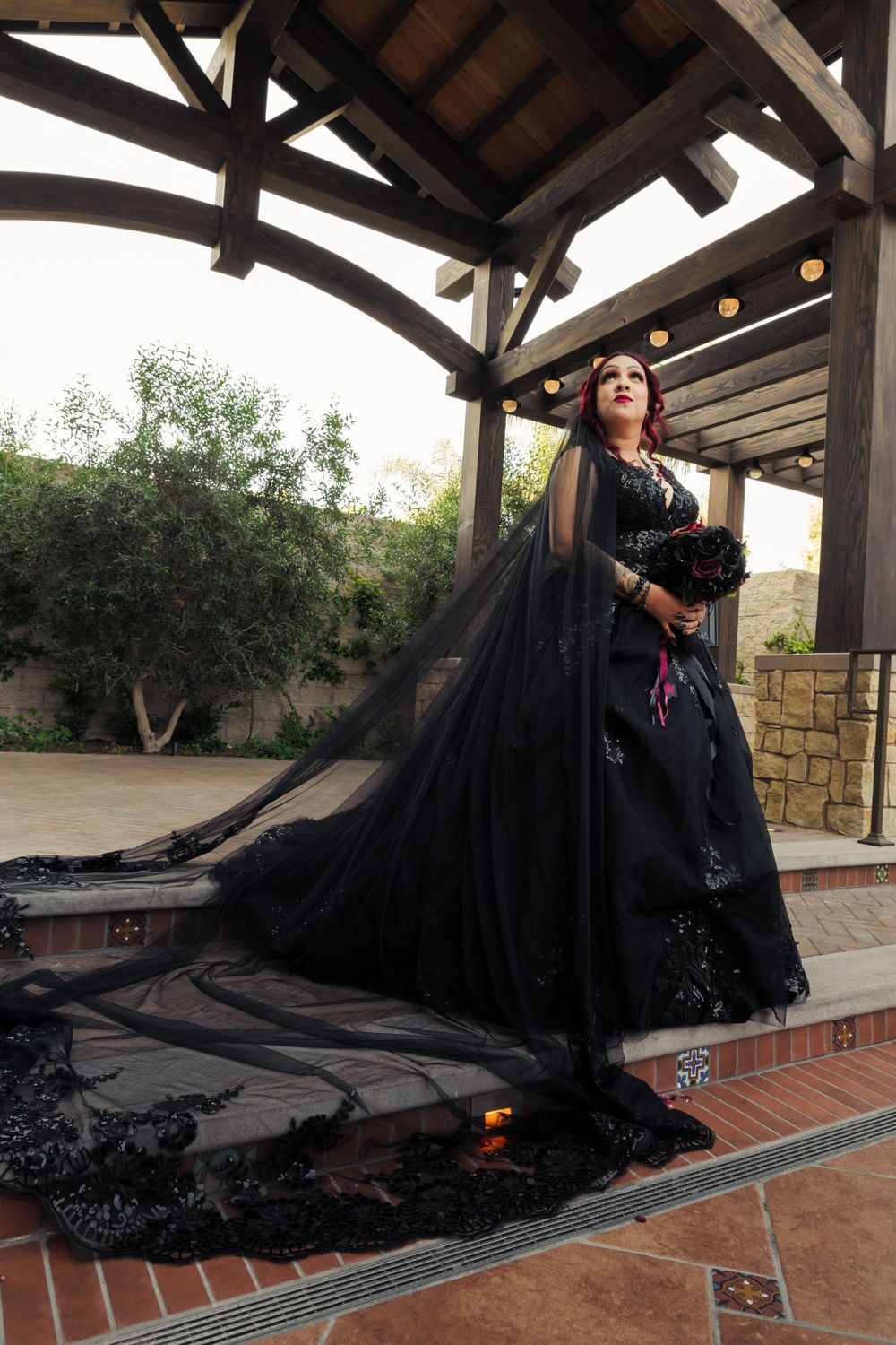 Bride in a black wedding dress poses elegantly outdoors, blending gothic style with classic wedding details, captured by Chris Cornish Photo