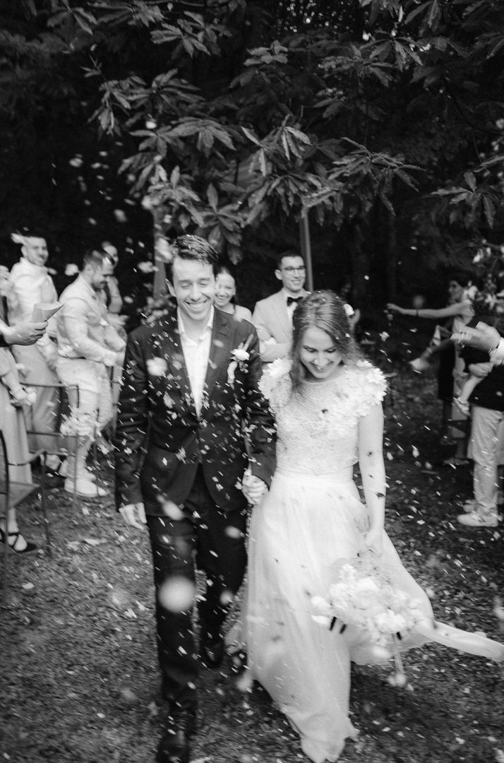 Wedding couple after exchanging vows – A newlywed couple shares a kiss beneath a floral arch at their wedding cere