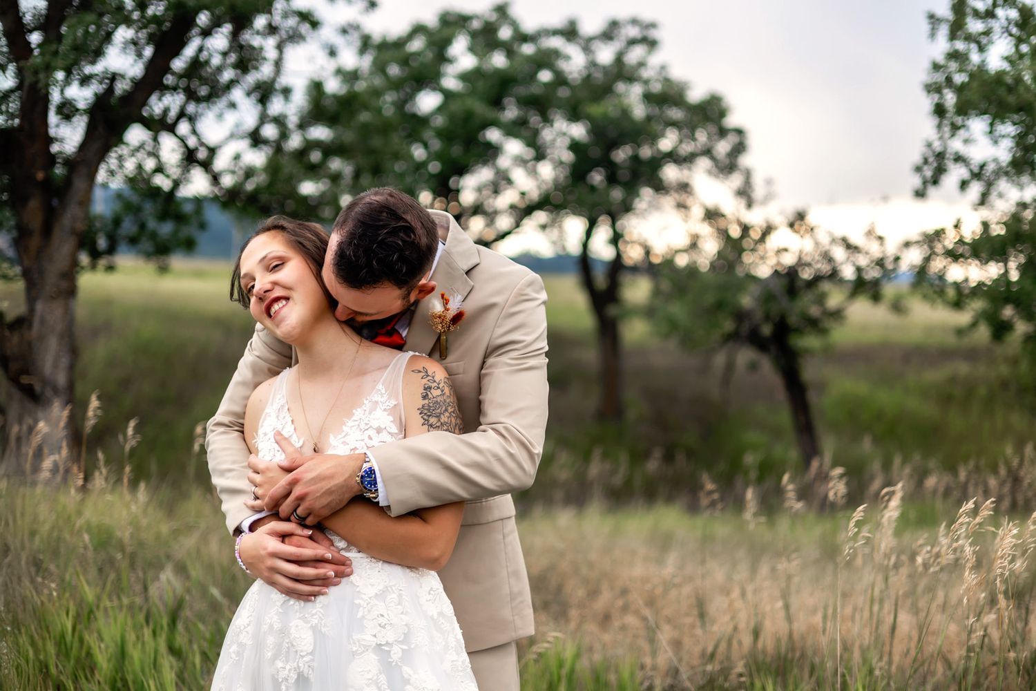 Wedding couple sharing intimate moment by large boulder in mountain landscape.