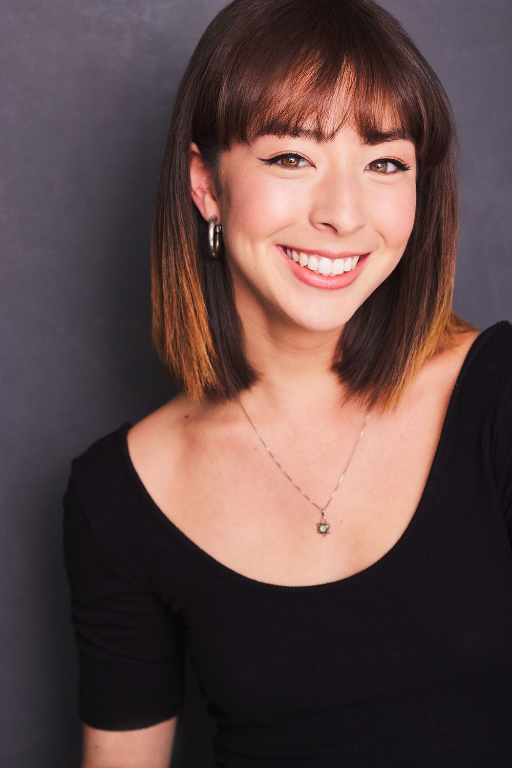 A series of professional headshots showing Aubrey Frances Anderson in a black top against a dark background with warm expressions.