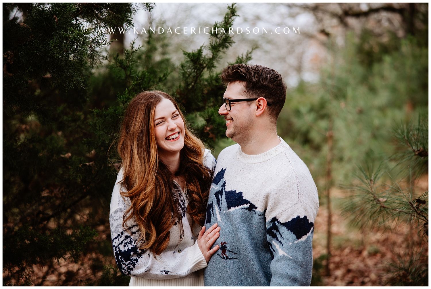 A couple shares a joyful moment together while laughing and embracing outdoors in a natural setting.