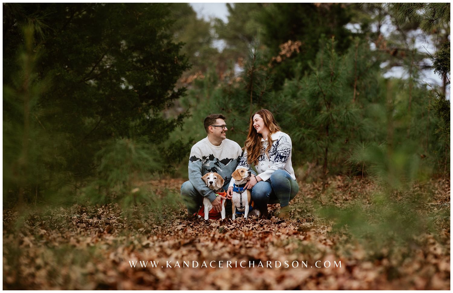 Family sitting together on fallen autumn leaves in a wooded outdoor setting during a photo session.