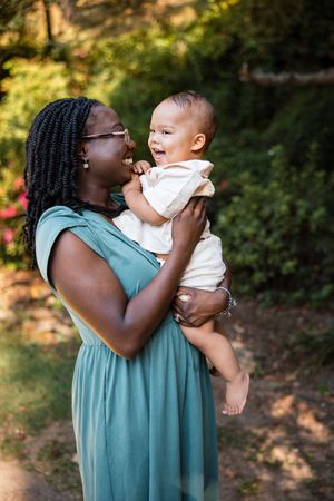 A tender moment captured in a series of photos showing a caregiver in a teal dress holding and kissing a baby outdoors.