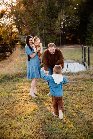 Family plays together in a grassy field during golden hour sunset, creating joyful moments and memories.