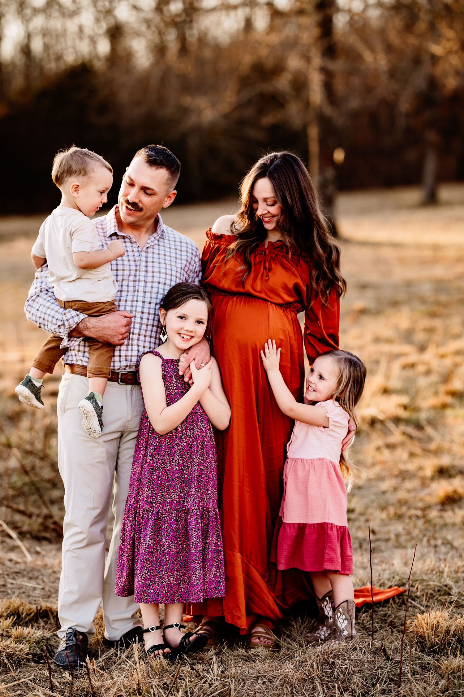 A family in coordinating red and purple outfits shares joyful moments together during an autumn outdoor photoshoot.