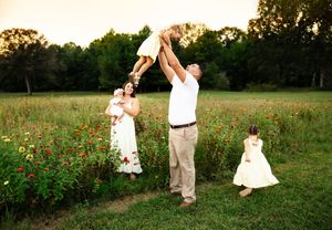 A couple dances together in a wildflower field at sunset during a romantic outdoor photo session.