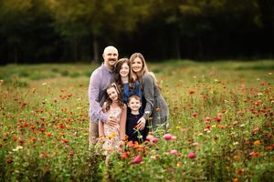 A family enjoying a beautiful autumn day together in a vibrant field of red wildflowers during golden hour.
