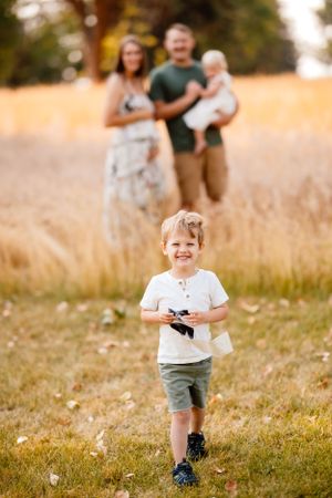 Joyful moment in a golden field as family stands together during sunset.