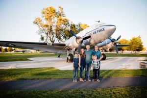 A vintage DC-3 aircraft serves as backdrop for an aviation-themed outdoor family photo session.