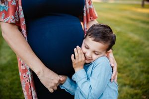 A tender maternity moment captured as a young child embraces an expectant mother's belly.