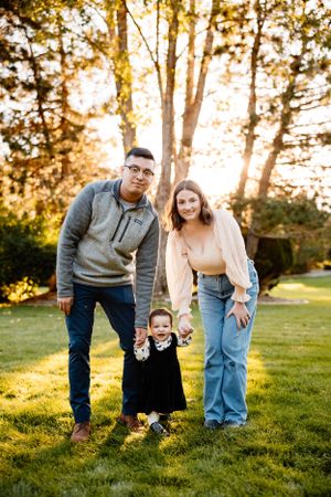 A family enjoys a playful moment together in a sunlit backyard setting.