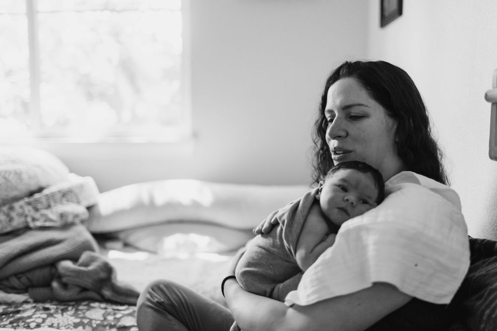 Everett Fresh 48 photographer: A mother holds her newborn baby on her bed at a fresh 48 photography session in Everett WA